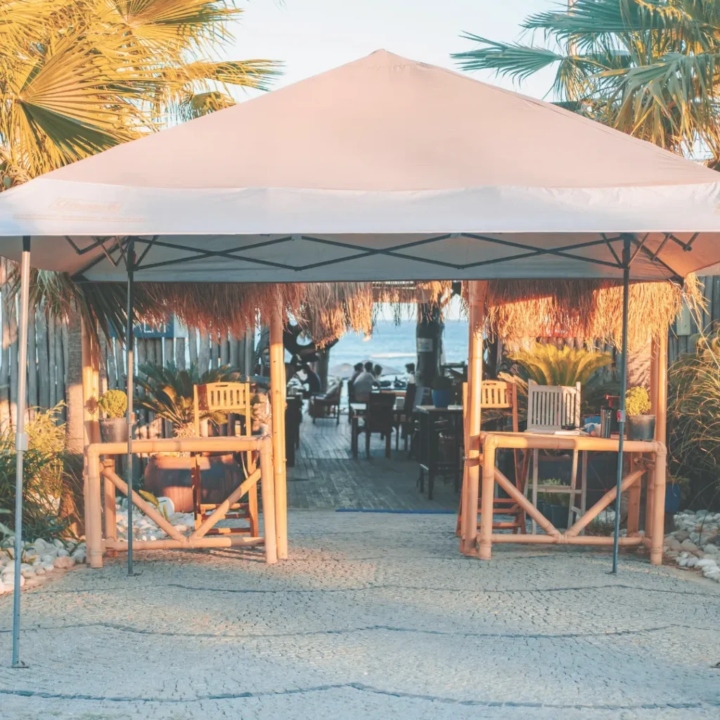 Ευέλικτο σύστημα σκίασης τύπου γκαζεμπό στην είσοδο παραθαλάσσιου εστιατορίου με φοίνικες.