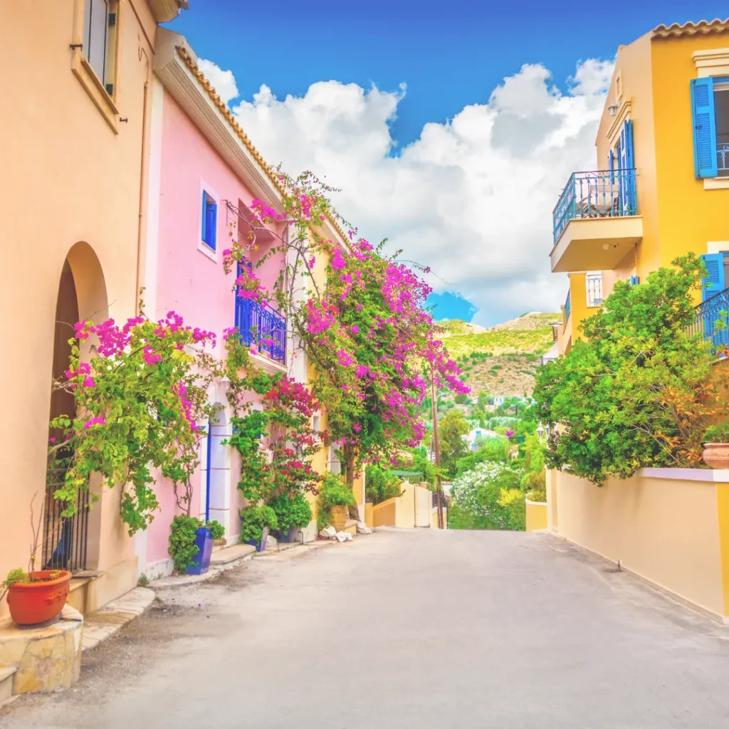 Γραφικό σοκάκι σε ελληνικό νησί με παραδοσιακά χρωματιστά σπίτια και ανθισμένες ροζ μπουκαμβίλιες.