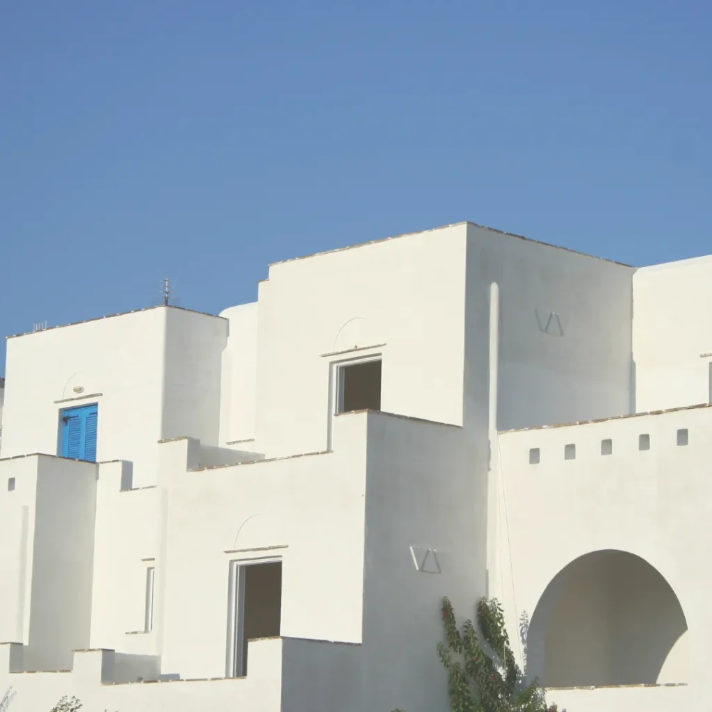 Σύγχρονη εξοχική κατοικία σε κυκλαδίτικο στιλ με λιτούς λευκούς όγκους και χαρακτηριστικό μπλε παντζούρι.