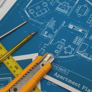 Εργαλεία μέτρησης και κοπίδι πάνω σε αρχιτεκτονικά σχέδια για ακριβή προϋπολογισμό