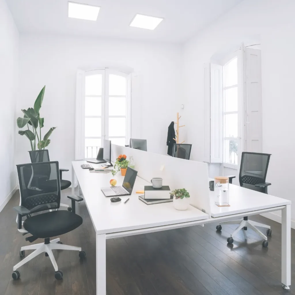 Φωτεινός και ευέλικτος χώρος εργασίας (agile workspace) με μεγάλα λευκά τραπέζια συνεργασίας και εργονομικές καρέκλες γραφείου.