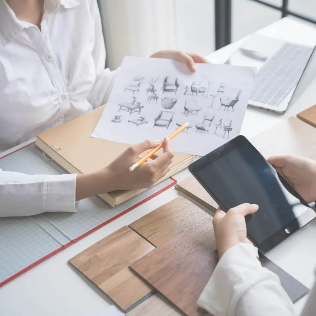 Σχεδιαστές της Idicon εξετάζουν σχέδια επίπλων και δείγματα υλικών για την ανακαίνιση και διαμόρφωση ενός παραγωγικού επαγγελματικού χώρου.